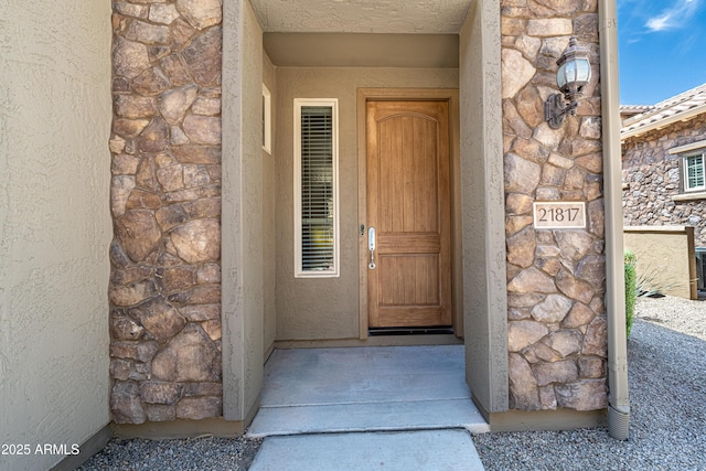property entrance with stone siding and stucco siding