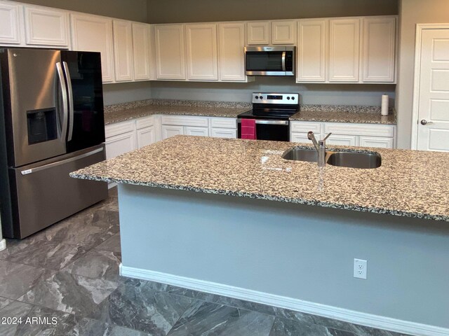 kitchen featuring light stone countertops, white cabinetry, sink, and appliances with stainless steel finishes