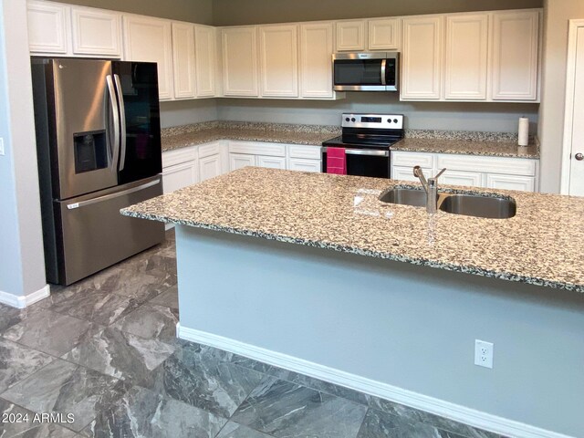 kitchen with light stone countertops, white cabinets, sink, and stainless steel appliances