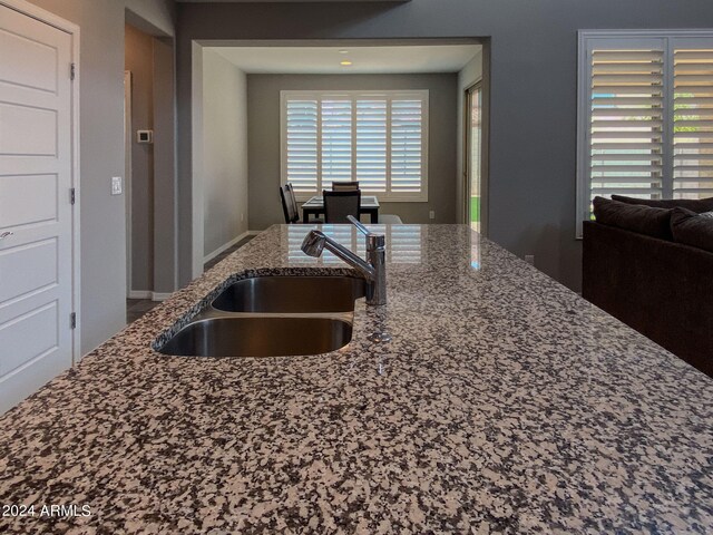 kitchen featuring a wealth of natural light, sink, and light stone counters