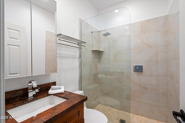 bathroom featuring vanity, tiled shower, and toilet