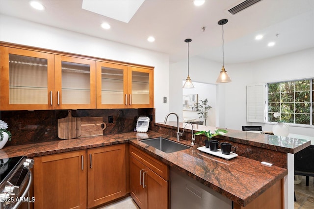 kitchen featuring sink, stainless steel range with electric cooktop, hanging light fixtures, kitchen peninsula, and dark stone counters