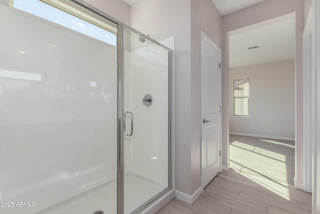 bathroom featuring a stall shower, wood finished floors, visible vents, and baseboards