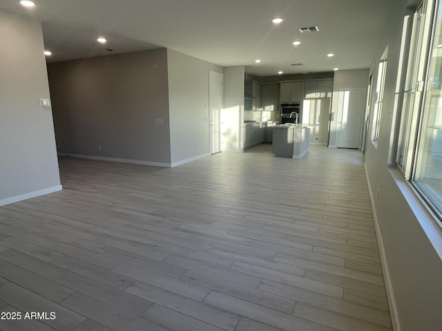 unfurnished living room featuring light wood-style floors, baseboards, visible vents, and recessed lighting