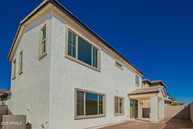 rear view of house featuring a patio, stucco siding, fence, and central air condition unit