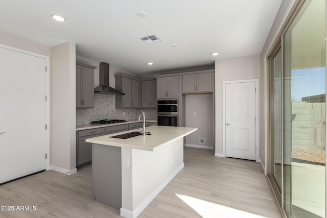 kitchen with wall chimney exhaust hood, visible vents, and gray cabinets