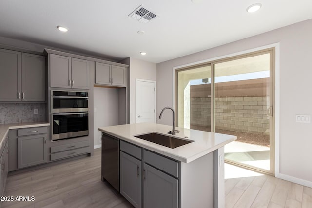 kitchen featuring double oven, visible vents, gray cabinets, and a sink