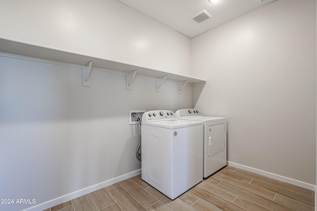 laundry area with light hardwood / wood-style flooring and washer and clothes dryer