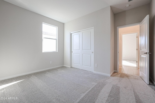 unfurnished bedroom featuring light colored carpet and a closet