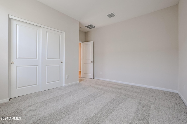 unfurnished bedroom featuring light colored carpet and a closet