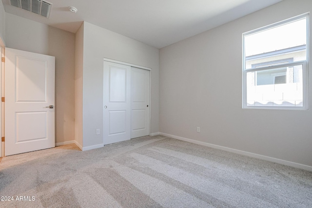 unfurnished bedroom featuring a closet and light colored carpet