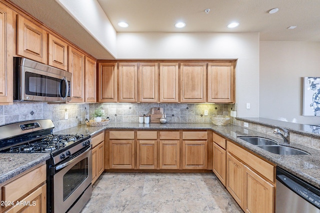 kitchen with backsplash, appliances with stainless steel finishes, sink, and stone countertops