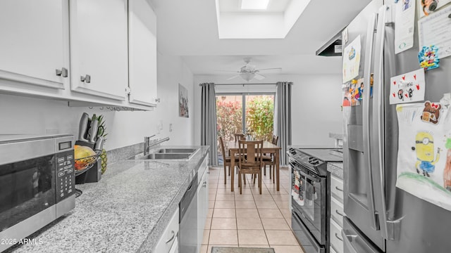 10420 N 10th St Unit 2, Phoenix, AZ 85020 - kitchen with stainless steel appliances, a sink, white cabinets, light tile patterned flooring, and a skylight