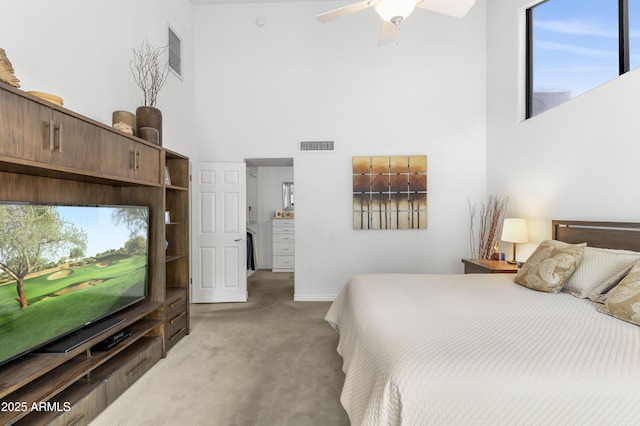 bedroom with visible vents, a towering ceiling, and light carpet