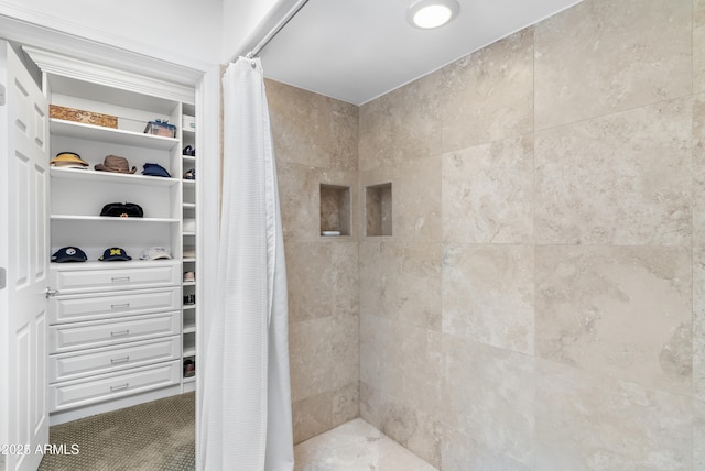 full bathroom featuring a tile shower and a walk in closet