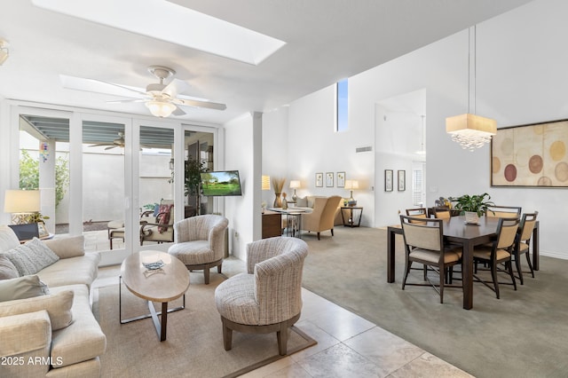 carpeted living room with visible vents, floor to ceiling windows, a skylight, and a ceiling fan