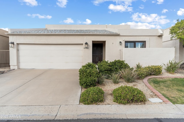 view of front of property featuring stucco siding, concrete driveway, a garage, and fence