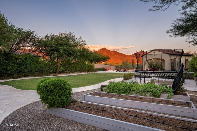 patio terrace at dusk featuring a mountain view, a pool with hot tub, and a fire pit