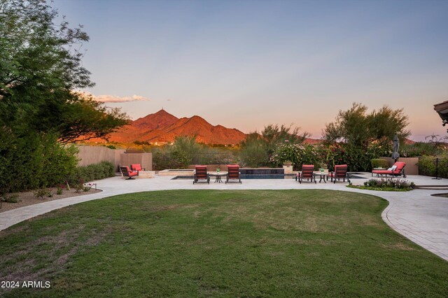 pool at dusk with a mountain view, a patio, and an in ground hot tub