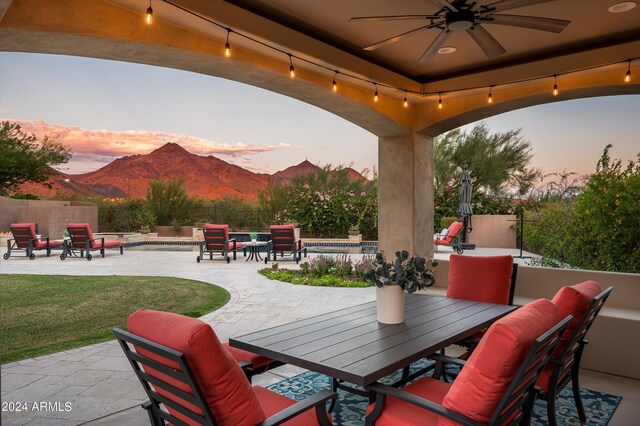 pool at dusk featuring a patio area, a mountain view, and an in ground hot tub