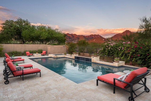 pool at dusk featuring a mountain view, a fire pit, and a patio