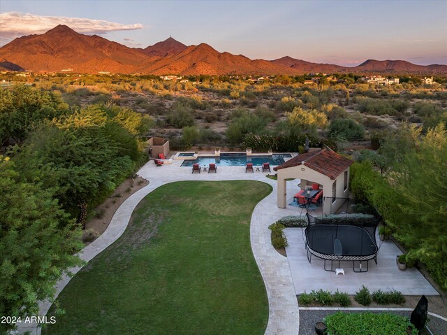 pool at dusk with a patio area, a mountain view, an outdoor fire pit, and an in ground hot tub