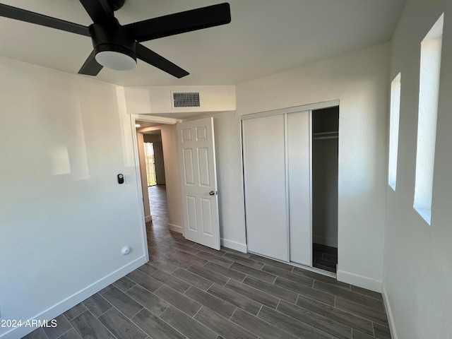 unfurnished bedroom with dark hardwood / wood-style flooring, ceiling fan, and a closet