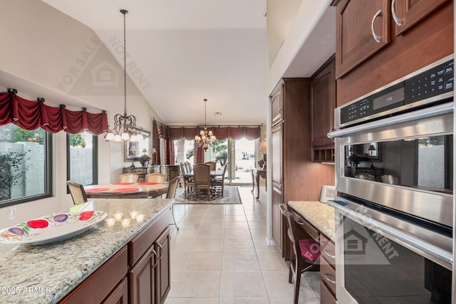 kitchen with light stone counters, light tile patterned floors, lofted ceiling, stainless steel double oven, and a chandelier