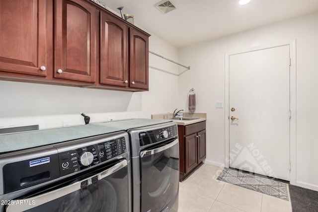 washroom with cabinet space, visible vents, washing machine and clothes dryer, a sink, and light tile patterned flooring