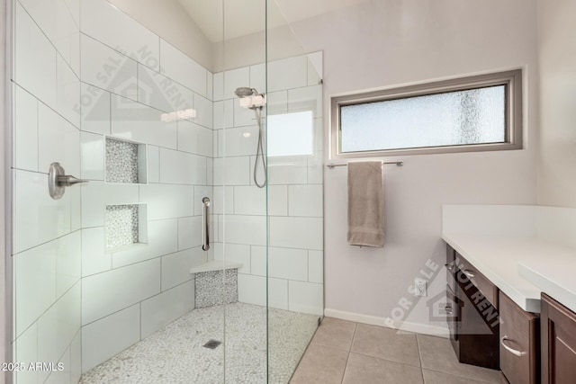 full bathroom with tiled shower, vanity, baseboards, and tile patterned floors