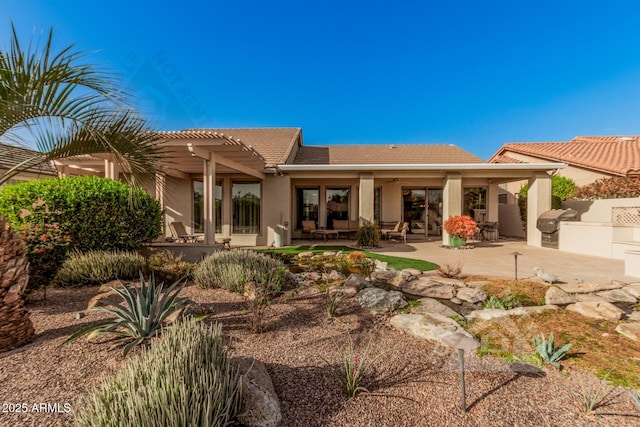 back of house featuring a tile roof, a patio area, outdoor lounge area, a pergola, and stucco siding