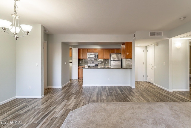 kitchen with backsplash, an inviting chandelier, hanging light fixtures, dark hardwood / wood-style floors, and stainless steel appliances