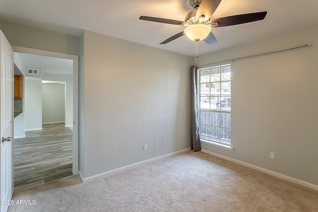 carpeted spare room featuring ceiling fan