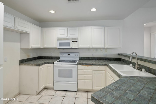 kitchen featuring white cabinetry, sink, light tile patterned floors, and white appliances