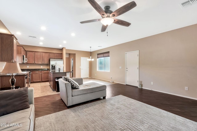 living room with dark hardwood / wood-style flooring and ceiling fan with notable chandelier