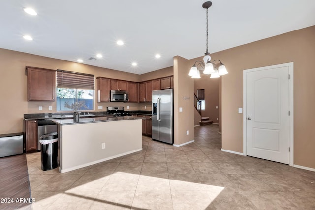 kitchen with a center island, pendant lighting, appliances with stainless steel finishes, light tile patterned floors, and a chandelier