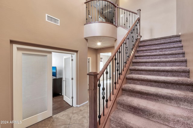 staircase with a high ceiling and tile patterned floors