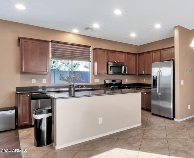 kitchen with appliances with stainless steel finishes, a center island, and light tile patterned flooring