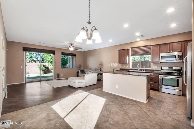 kitchen featuring ceiling fan with notable chandelier, hanging light fixtures, appliances with stainless steel finishes, and a center island