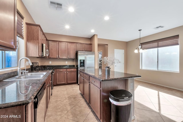 kitchen featuring stainless steel appliances, a center island, a notable chandelier, pendant lighting, and sink