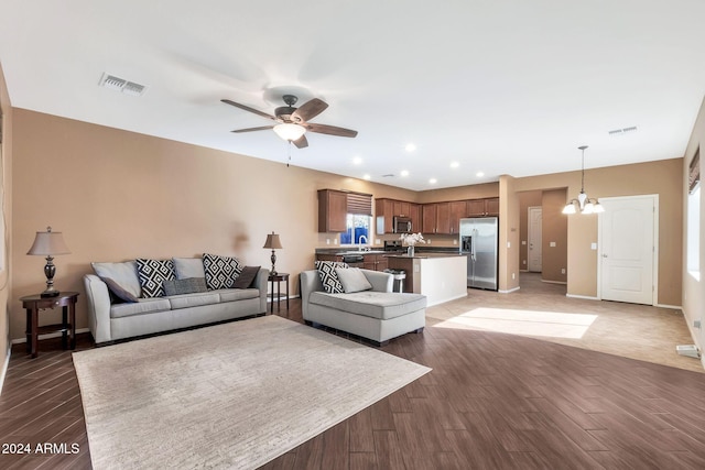 living room featuring dark hardwood / wood-style floors, sink, and ceiling fan with notable chandelier