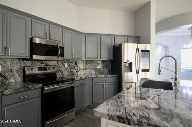 kitchen with sink, stone countertops, gray cabinetry, and stainless steel appliances