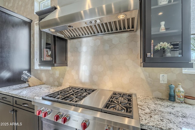 8768 E Granite Pass Rd, Scottsdale, AZ 85266 - kitchen featuring range hood, light stone countertops, tasteful backsplash, glass insert cabinets, and stovetop