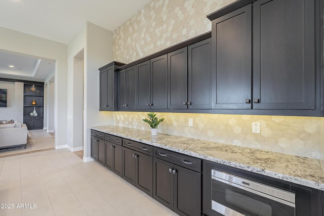 8768 E Granite Pass Rd, Scottsdale, AZ 85266 - kitchen featuring decorative backsplash, baseboards, stainless steel microwave, light stone counters, and light tile patterned floors