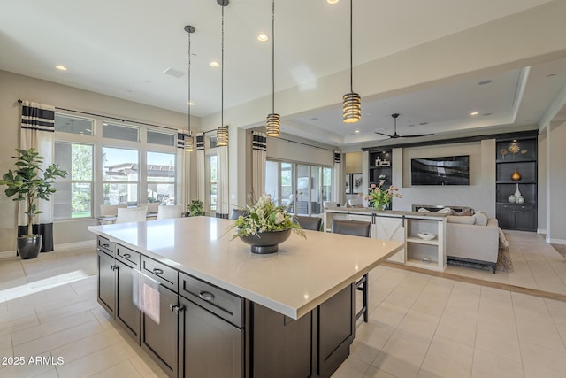 8768 E Granite Pass Rd, Scottsdale, AZ 85266 - kitchen featuring a tray ceiling, light countertops, a ceiling fan, a kitchen island, and open floor plan