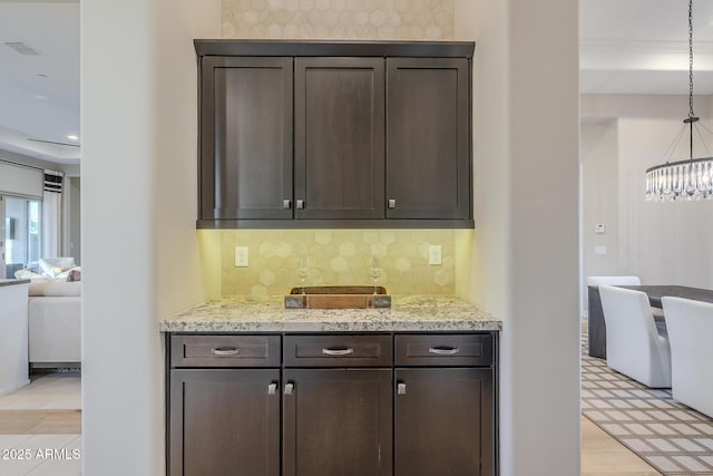 8768 E Granite Pass Rd, Scottsdale, AZ 85266 - kitchen featuring decorative backsplash, visible vents, a chandelier, dark brown cabinets, and light stone counters