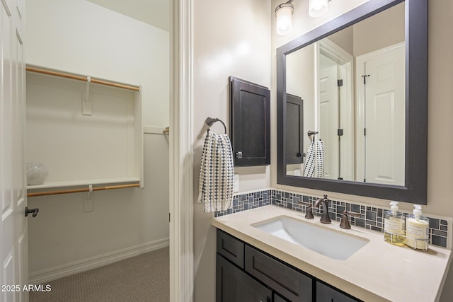 8768 E Granite Pass Rd, Scottsdale, AZ 85266 - bathroom with baseboards, a walk in closet, vanity, and tasteful backsplash