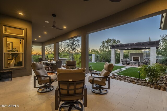 8768 E Granite Pass Rd, Scottsdale, AZ 85266 - patio terrace at dusk with an outdoor living space with a fireplace, outdoor dining space, a ceiling fan, and a pergola