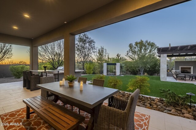 8768 E Granite Pass Rd, Scottsdale, AZ 85266 - patio terrace at dusk with an outdoor kitchen, fence, a pergola, a lawn, and outdoor dining area