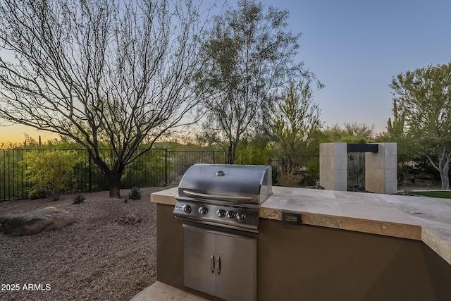 8768 E Granite Pass Rd, Scottsdale, AZ 85266 - patio terrace at dusk featuring an outdoor kitchen, area for grilling, and fence